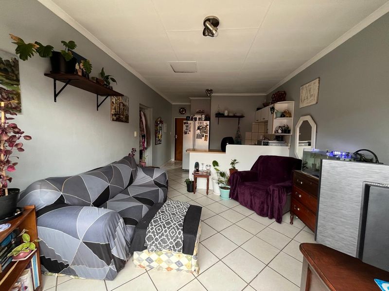 Open plan living area featuring tiled flooring and a breakfast bar connecting to the kitchen space.