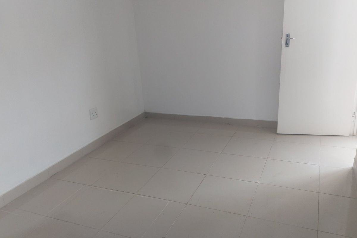 A clean, empty bedroom featuring neutral tiled flooring and white walls, providing a versatile blank canvas for any commercial or residential use.