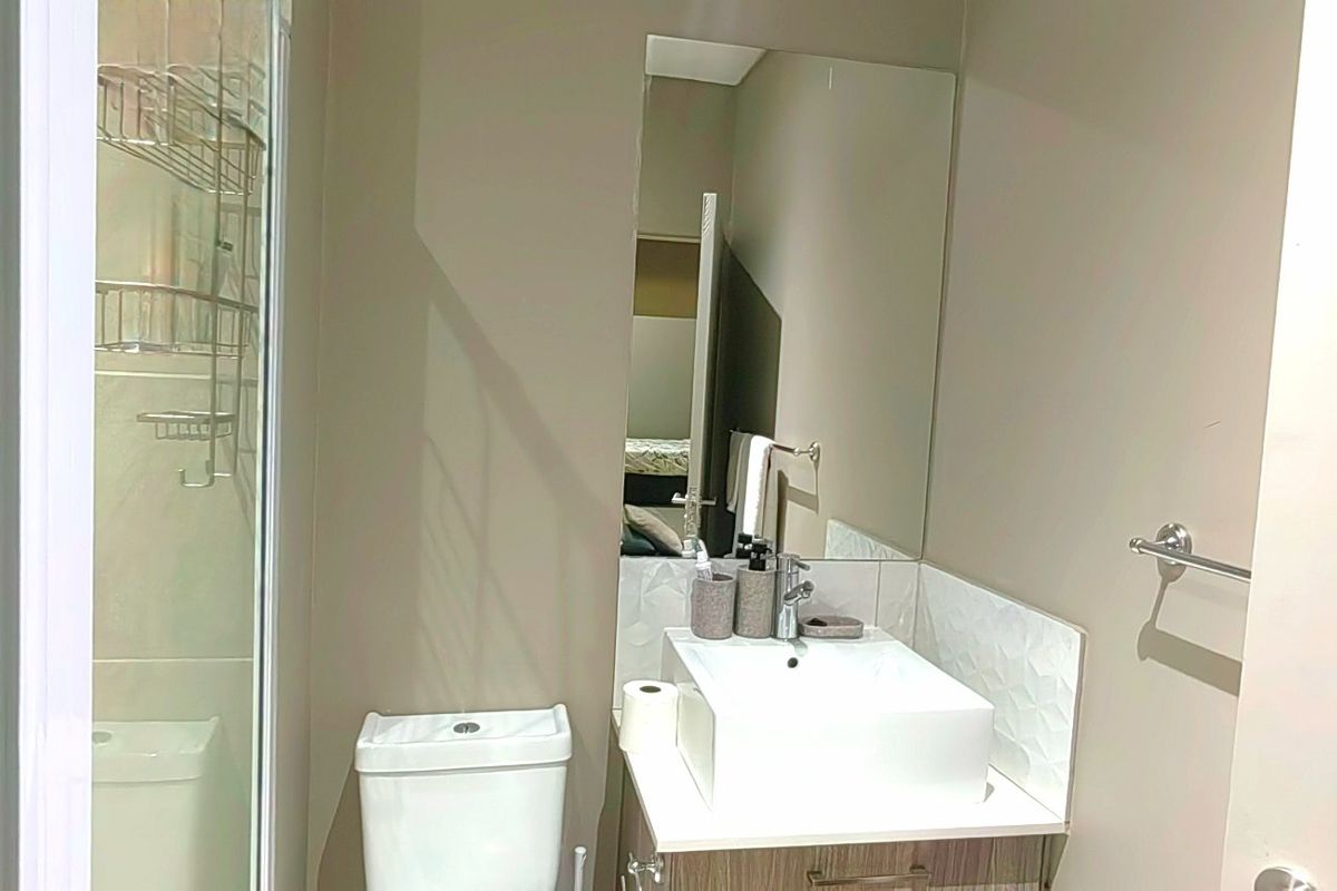 Modern bathroom featuring a glass shower enclosure, a vessel sink vanity with storage, and a large wall-mounted mirror.