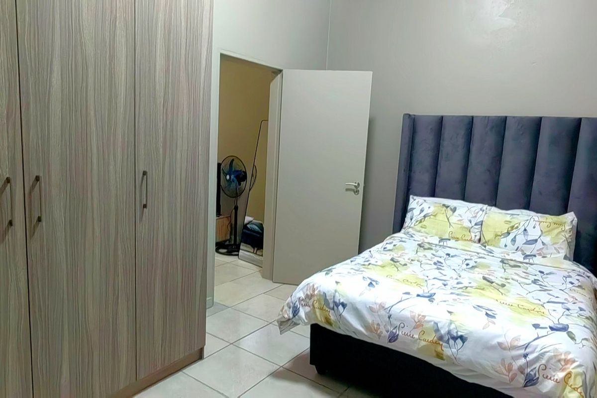 A bedroom featuring built-in cupboards and tiled flooring, providing a functional and clean living space.