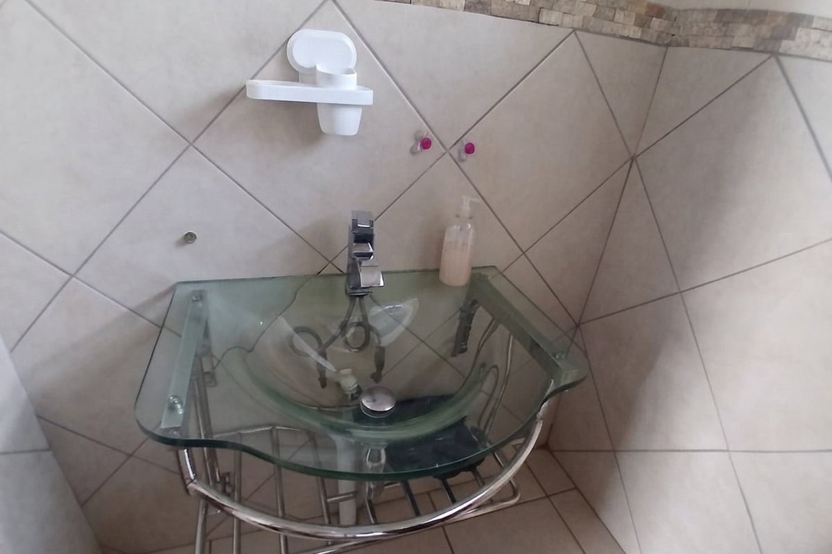 A bathroom vanity area featuring a modern glass vessel sink with chrome faucet and decorative tiled wall finishes.