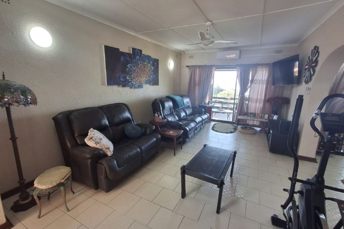 A spacious living room featuring tiled flooring, a ceiling fan, and a split-system air conditioner, with direct access to an outdoor patio area.