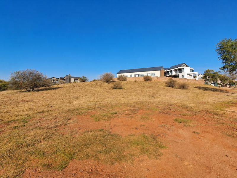 A view of a vacant residential plot of land with a gentle slope, situated in a developed neighborhood.