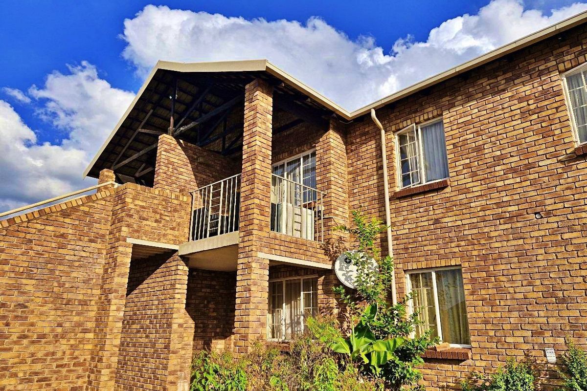 Exterior view of a face brick apartment building featuring a balcony and pitched roof design.