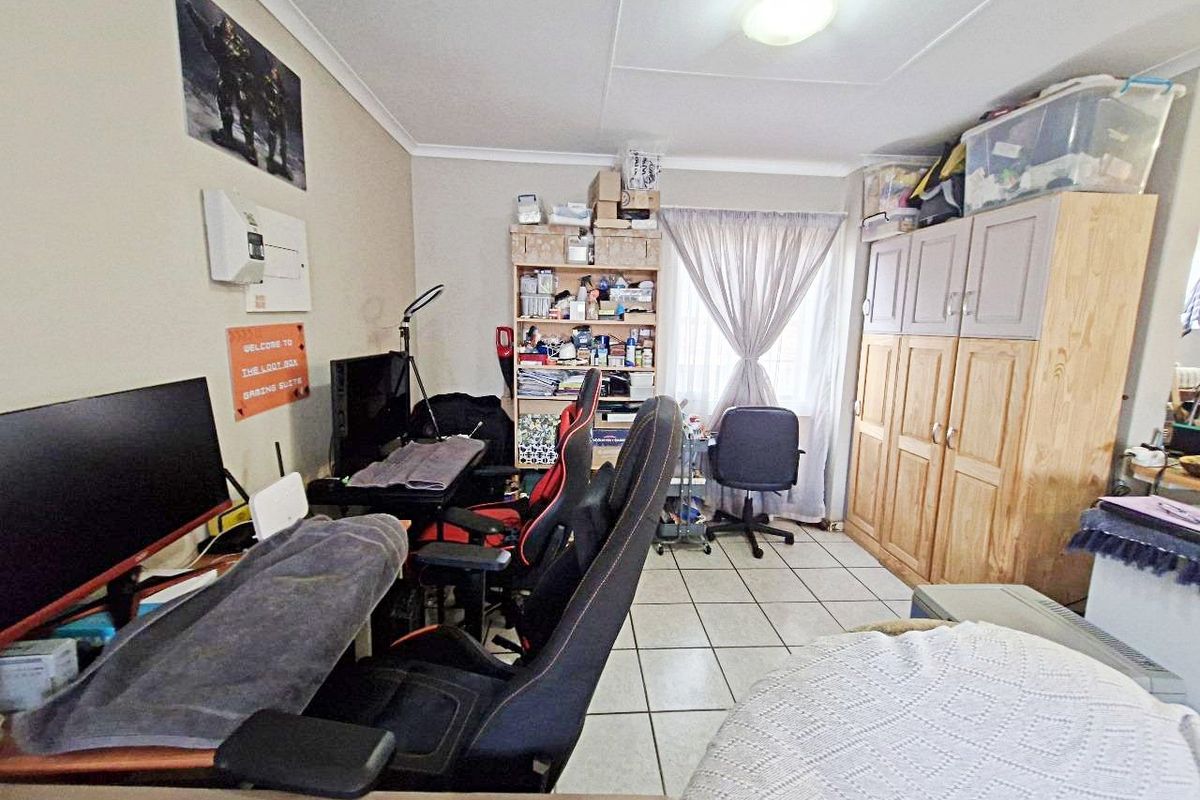 A bedroom featuring tiled flooring and a built-in wardrobe, currently utilized as a home office and gaming space.