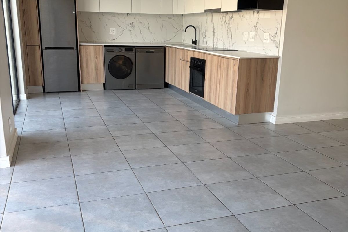 Modern kitchen featuring sleek two-tone cabinetry, marble-look splashback, integrated oven, and large format floor tiles in an open-plan layout.