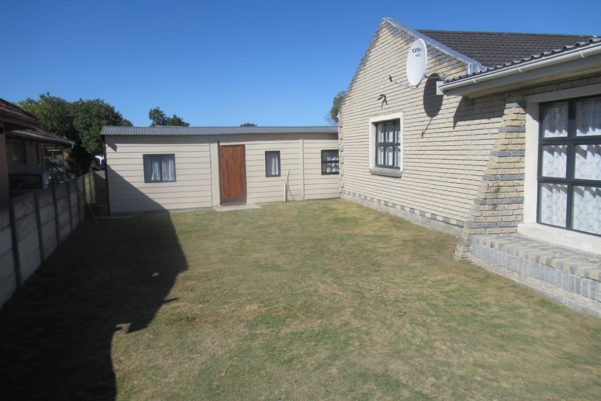 Rear view of the property featuring a face brick main house, a separate outbuilding, and a private garden area enclosed by a boundary wall.