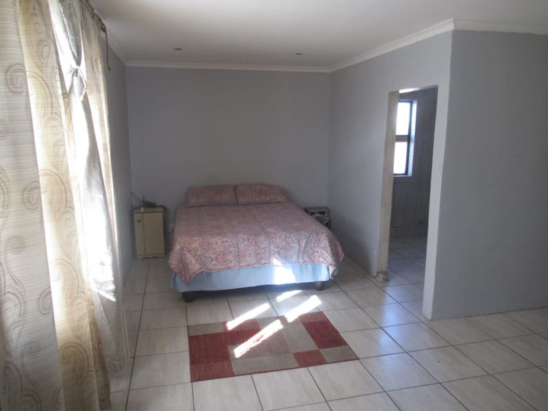 A functional bedroom featuring tiled flooring, recessed lighting, and a coved ceiling, with an adjoining space visible through the doorway.