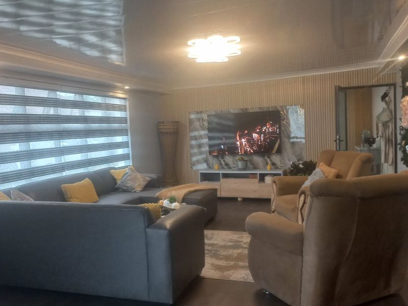 A comfortable living room featuring a glossy ceiling, tiled flooring, and a modern media wall with integrated television.