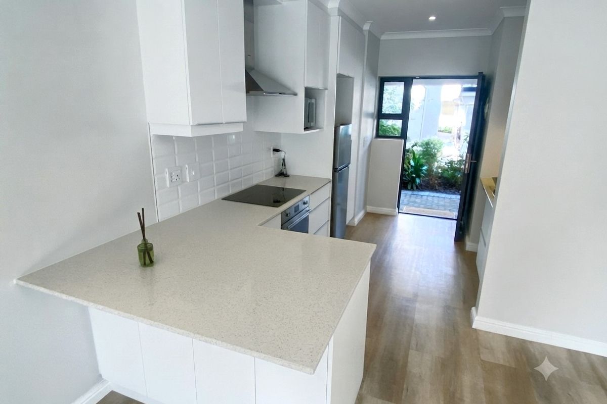Modern kitchen featuring white cabinetry, quartz countertops, subway tile backsplash, and integrated appliances, leading directly to an outdoor patio area.
