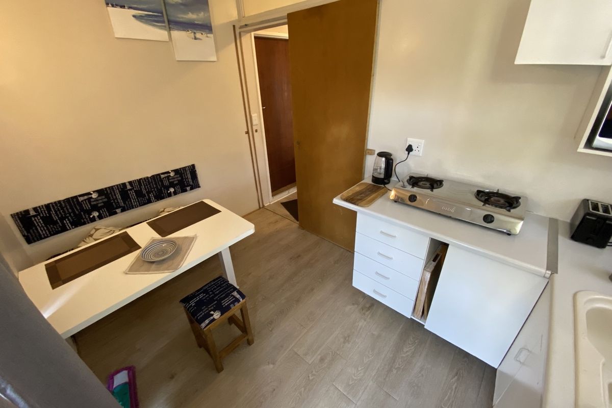 Compact kitchen area featuring laminate flooring, white cabinetry, and a gas cooktop, with an adjacent dining nook.