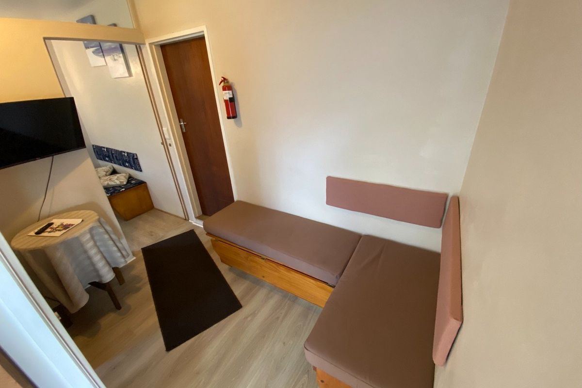 A compact living area featuring laminate flooring and built-in bench seating, providing a functional space within the apartment.