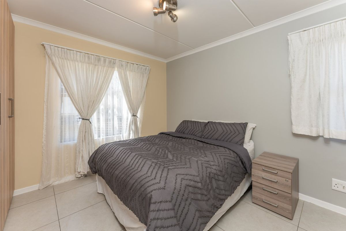 A well-maintained bedroom featuring tiled flooring, a built-in wardrobe, and neutral wall tones, providing a clean and functional living space.