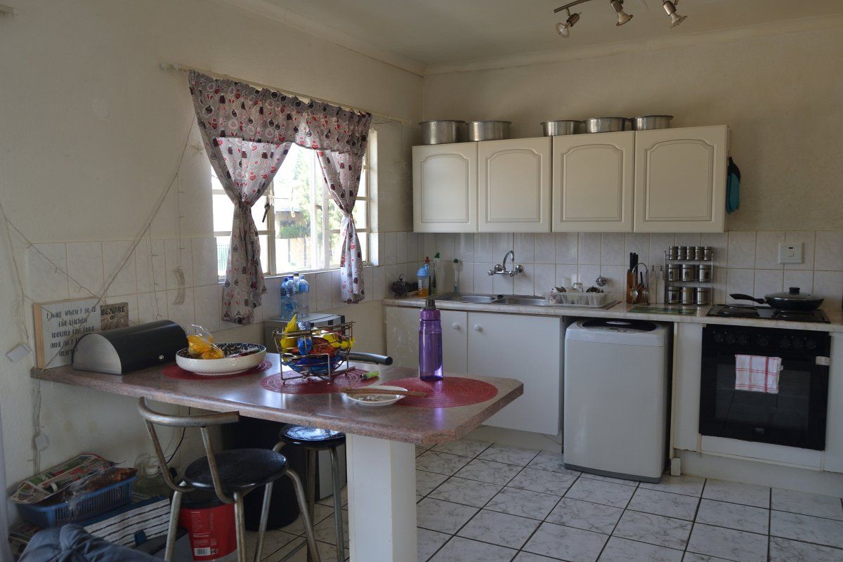 A functional kitchen featuring built-in cabinetry, tiled backsplash, integrated oven and hob, and a breakfast nook area with tiled flooring.