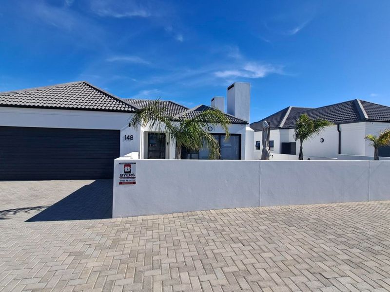 Modern single-story residential property featuring a paved driveway, double garage, and clean white exterior facade with a tiled roof.