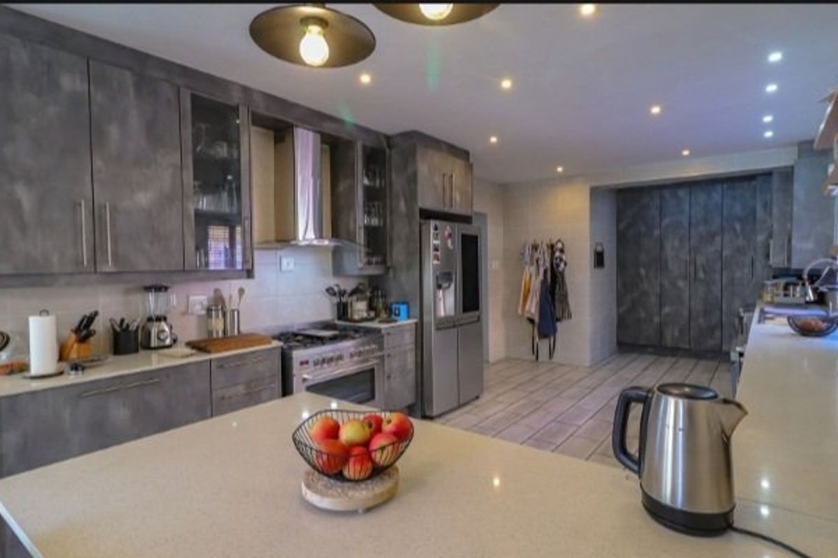 Modern kitchen featuring stone countertops, extensive built-in cabinetry, gas stove with extractor, and recessed lighting, offering a functional and stylish culinary space.