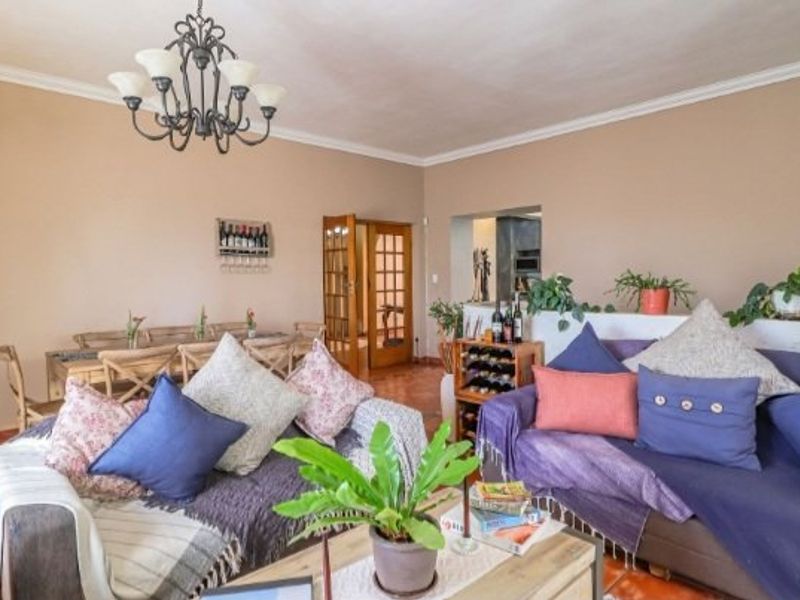 Spacious open-plan living and dining area featuring terracotta floor tiles, decorative coving, and a classic chandelier, providing a warm and inviting atmosphere.