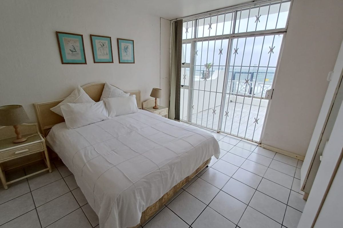 Bedroom featuring tiled flooring and a large sliding glass door with security gate, providing direct access to an outdoor balcony area.