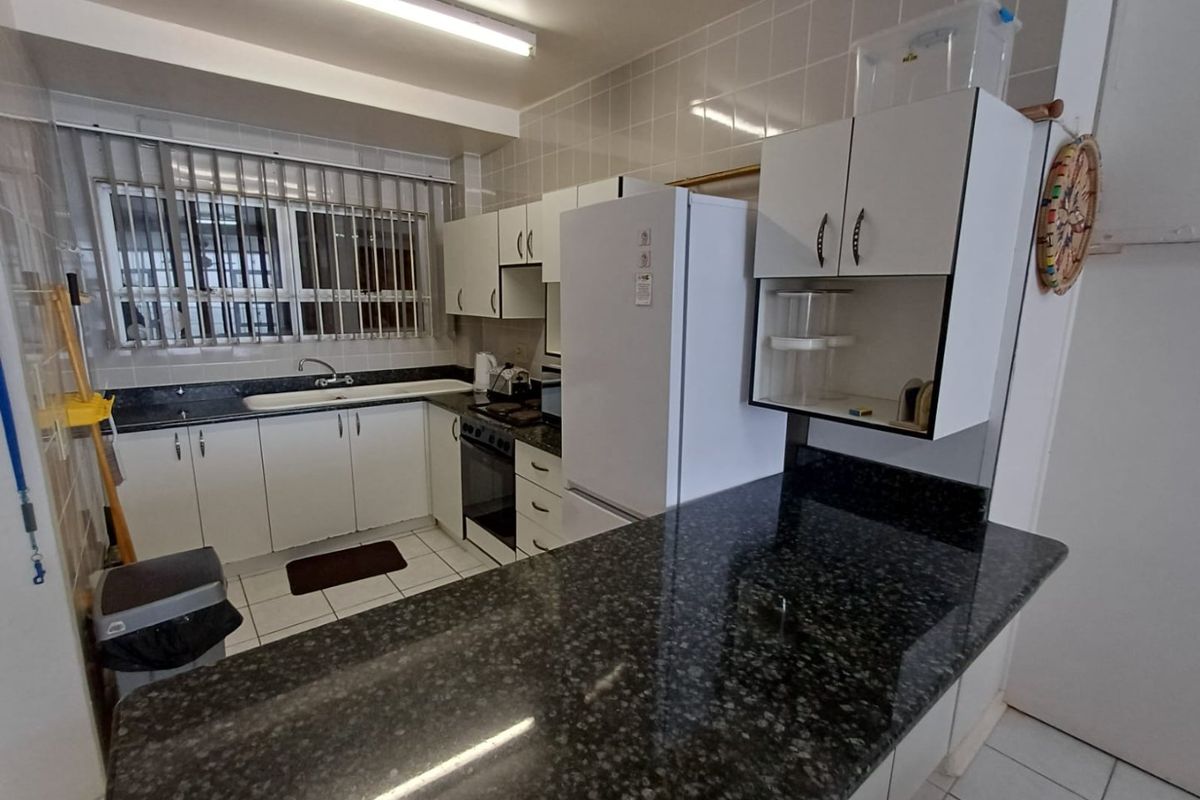 Functional kitchen featuring granite countertops, white cabinetry, ceramic tile backsplash, and a built-in oven, offering a practical layout for daily meal preparation.