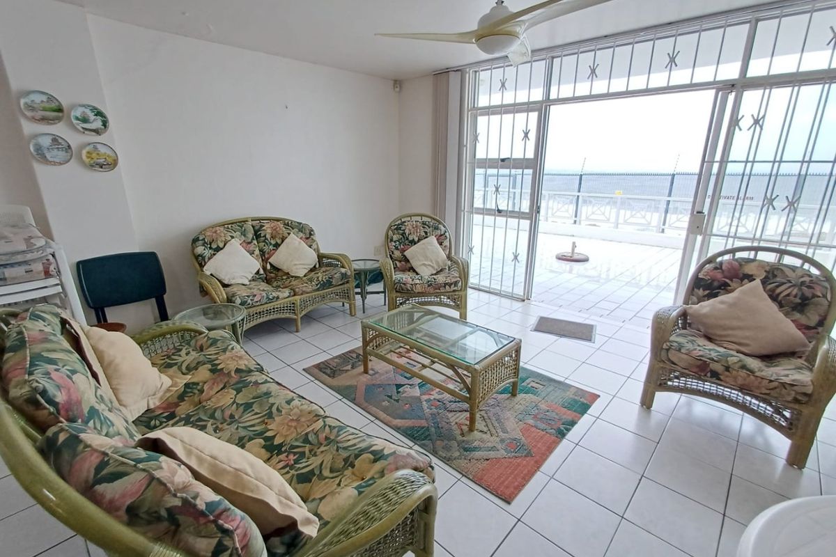 Spacious living area featuring tiled flooring, a ceiling fan, and large sliding glass doors providing access to an outdoor patio area.