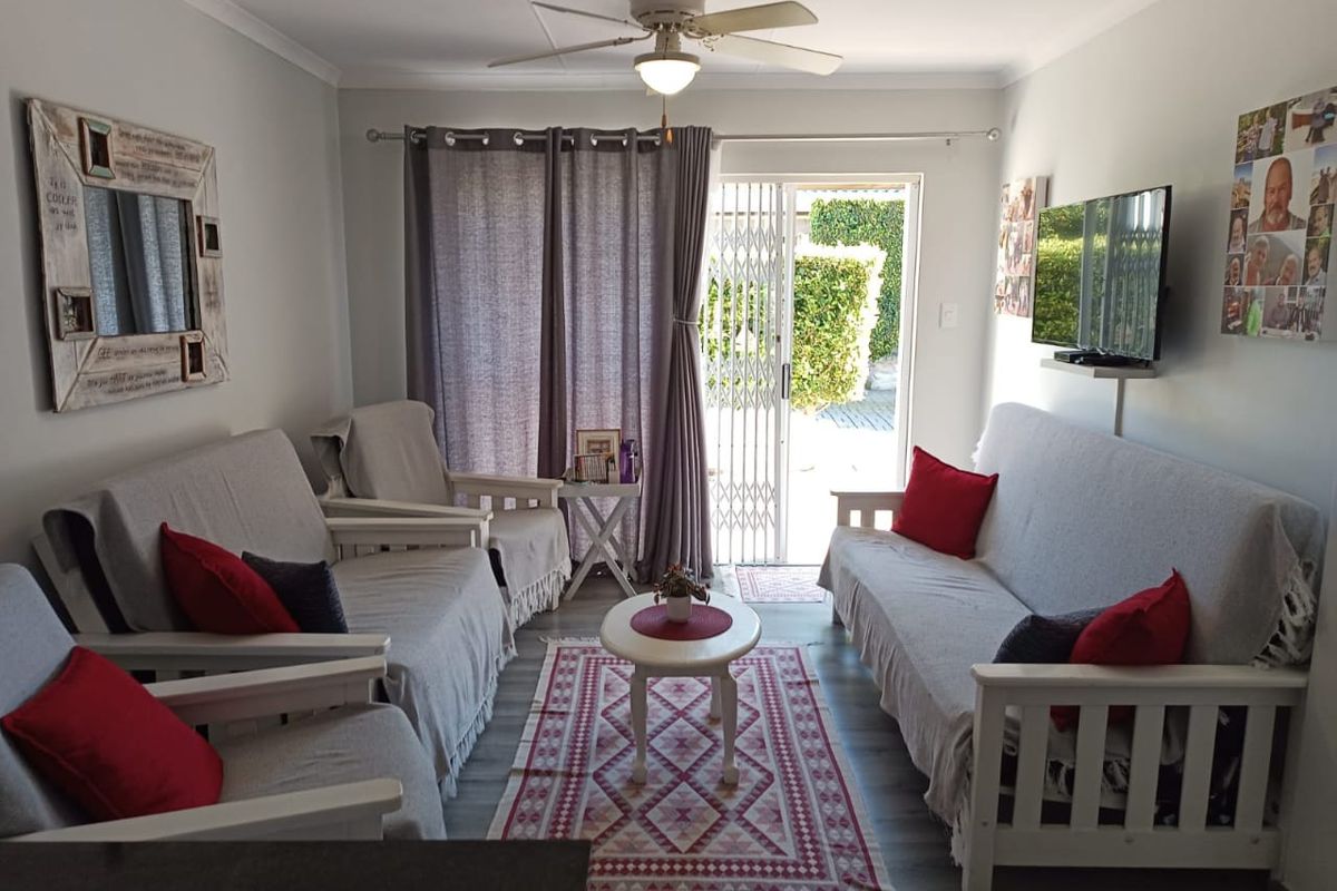 A comfortable living room featuring laminate flooring, a ceiling fan, and a sliding glass door providing direct access to the outdoor area.
