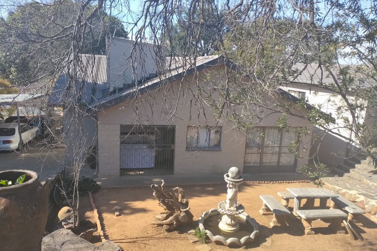 Rear view of the property featuring a paved courtyard area with a stone fountain, concrete seating, and direct access to the main dwelling.