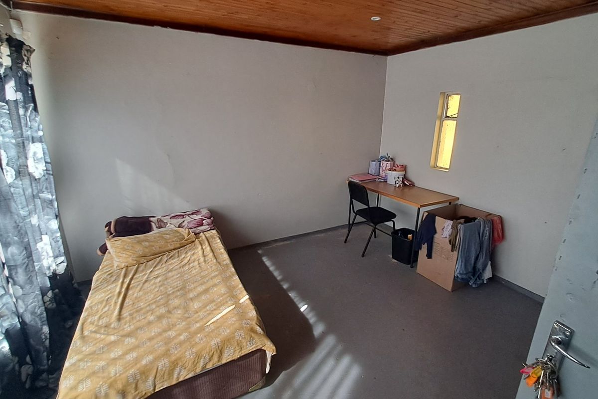 A simple bedroom featuring a timber ceiling and a vertical window, requiring cosmetic updates to improve the overall finish and appeal.