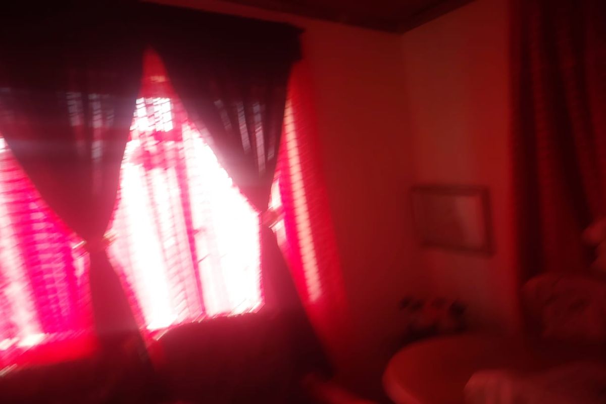A dimly lit bedroom interior with red curtains and poor image quality.