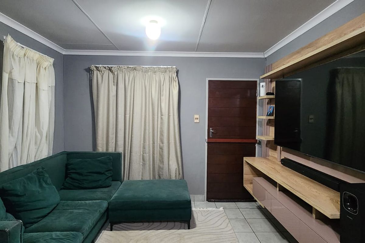 A living room featuring a built-in media unit, tiled flooring, and neutral grey walls.