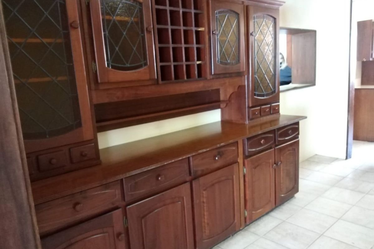 A kitchen area featuring extensive built-in wooden cabinetry with integrated wine storage and leaded glass display doors, complemented by ceramic tile flooring.