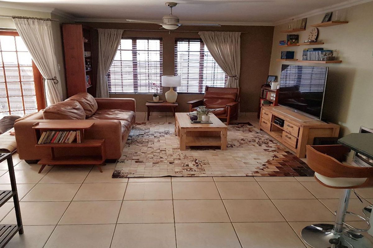 A comfortable living room featuring tiled flooring, a ceiling fan, and direct access to the outdoor area through french doors.