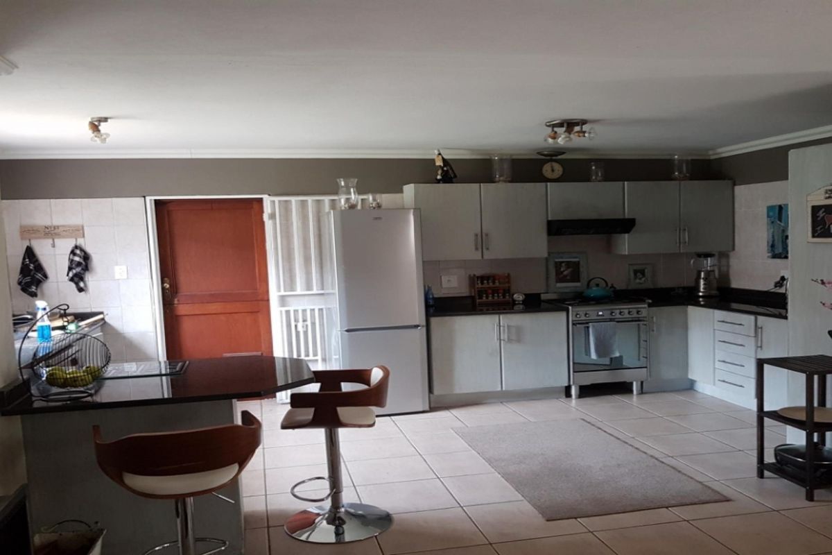 A functional kitchen featuring built-in cabinetry, granite countertops, a breakfast bar, and tiled flooring, providing a practical space for cooking and casual dining.