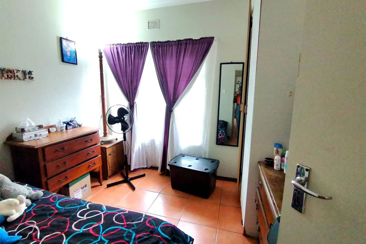 A standard bedroom featuring tiled flooring and a built-in cupboard, offering a functional space with natural light from the window.