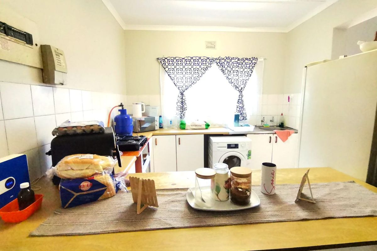 A functional kitchen featuring white cabinetry, laminate countertops, and a tiled splashback, offering a practical layout for daily meal preparation.