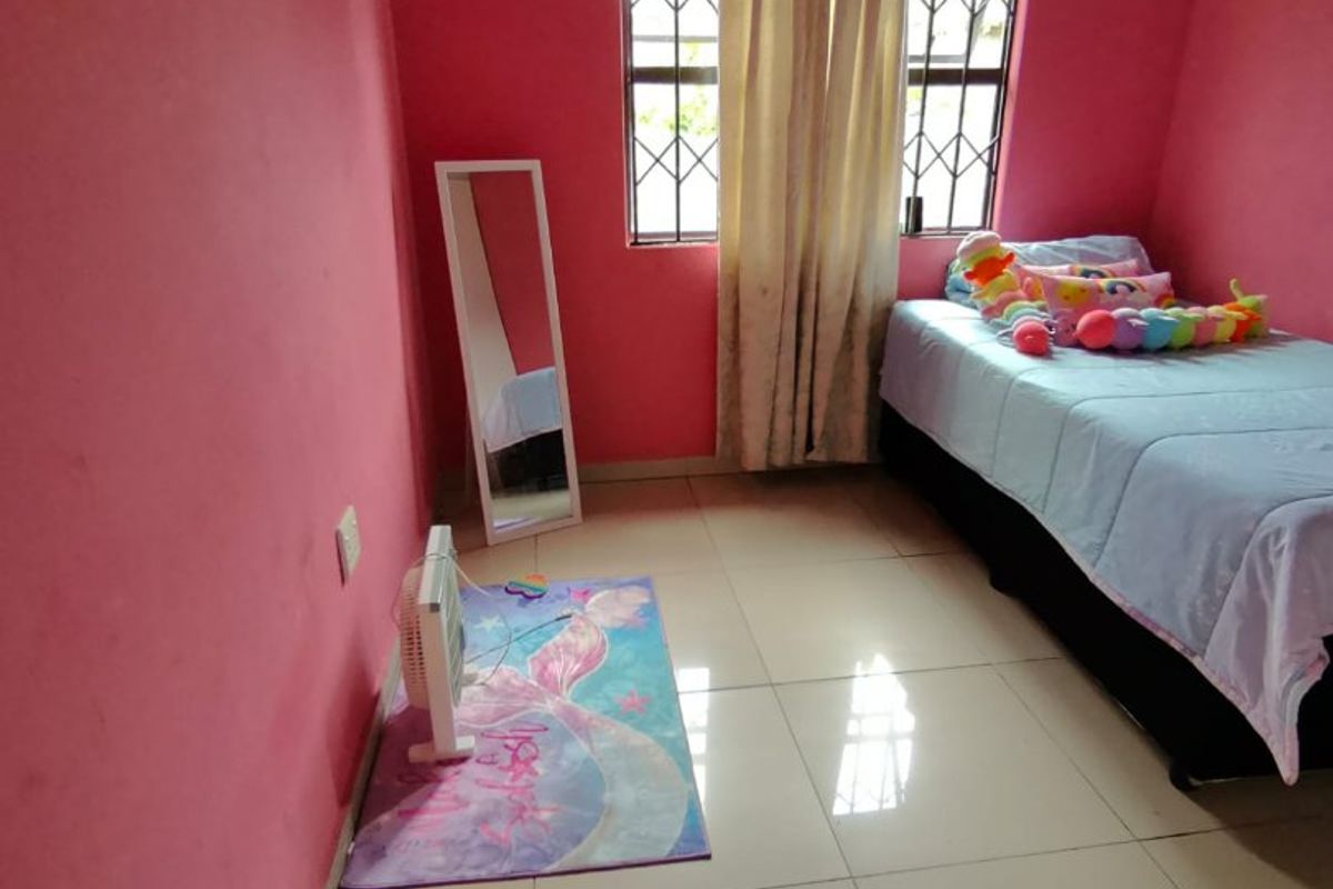A bedroom featuring tiled flooring and windows fitted with security bars, finished with bright pink wall paint.