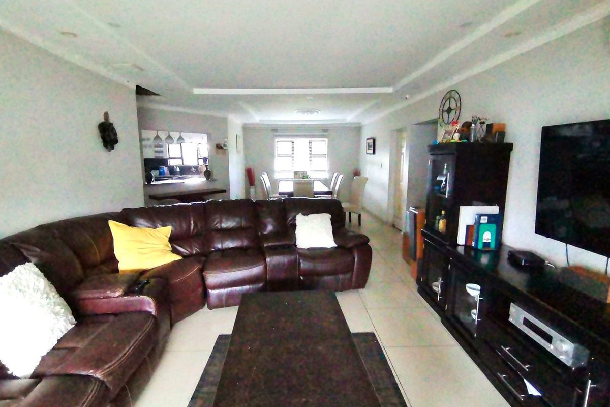 Spacious open-plan living area featuring tiled flooring, recessed ceiling lighting, and a seamless flow into the adjacent dining and kitchen spaces.