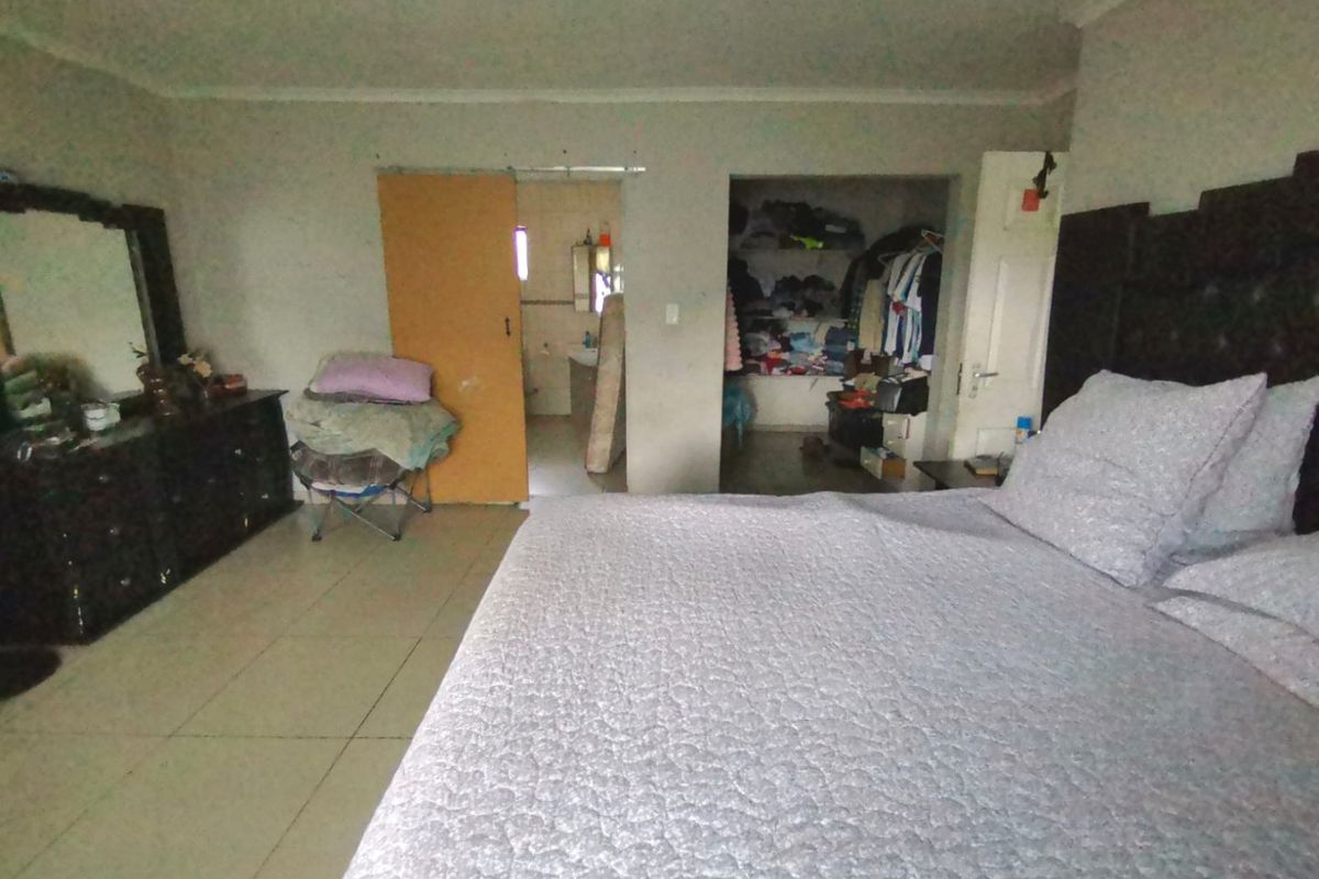 Spacious bedroom featuring tiled flooring, built-in cupboards, and direct access to an en-suite bathroom.