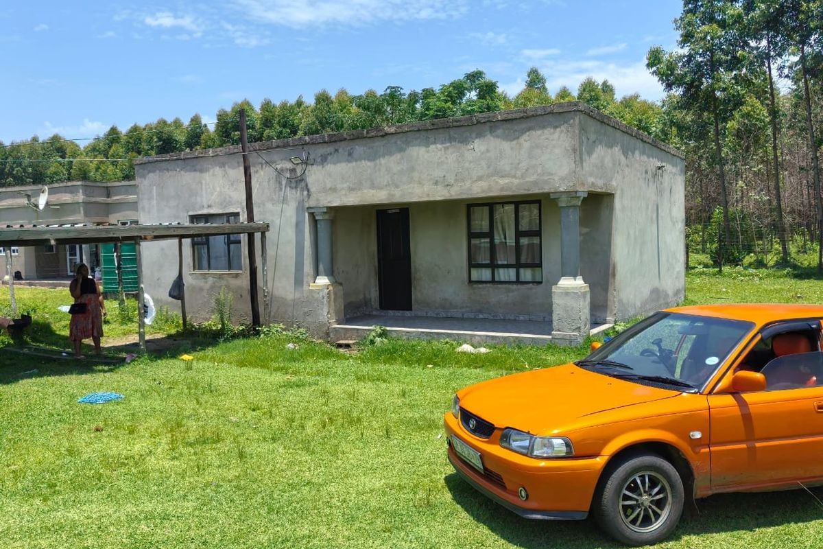Front view of a single-story house featuring an unfinished concrete facade and a covered porch area.