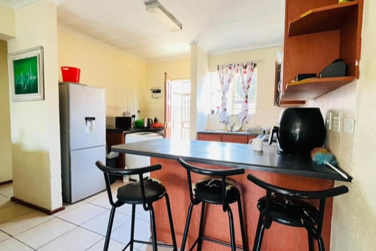 A functional kitchen featuring a breakfast bar, laminate cabinetry, and tiled flooring, offering a practical layout with direct access to the exterior.