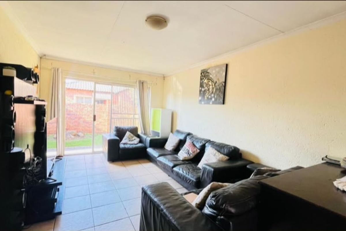 A living room featuring tiled flooring and a sliding glass door providing access to the outdoor area.