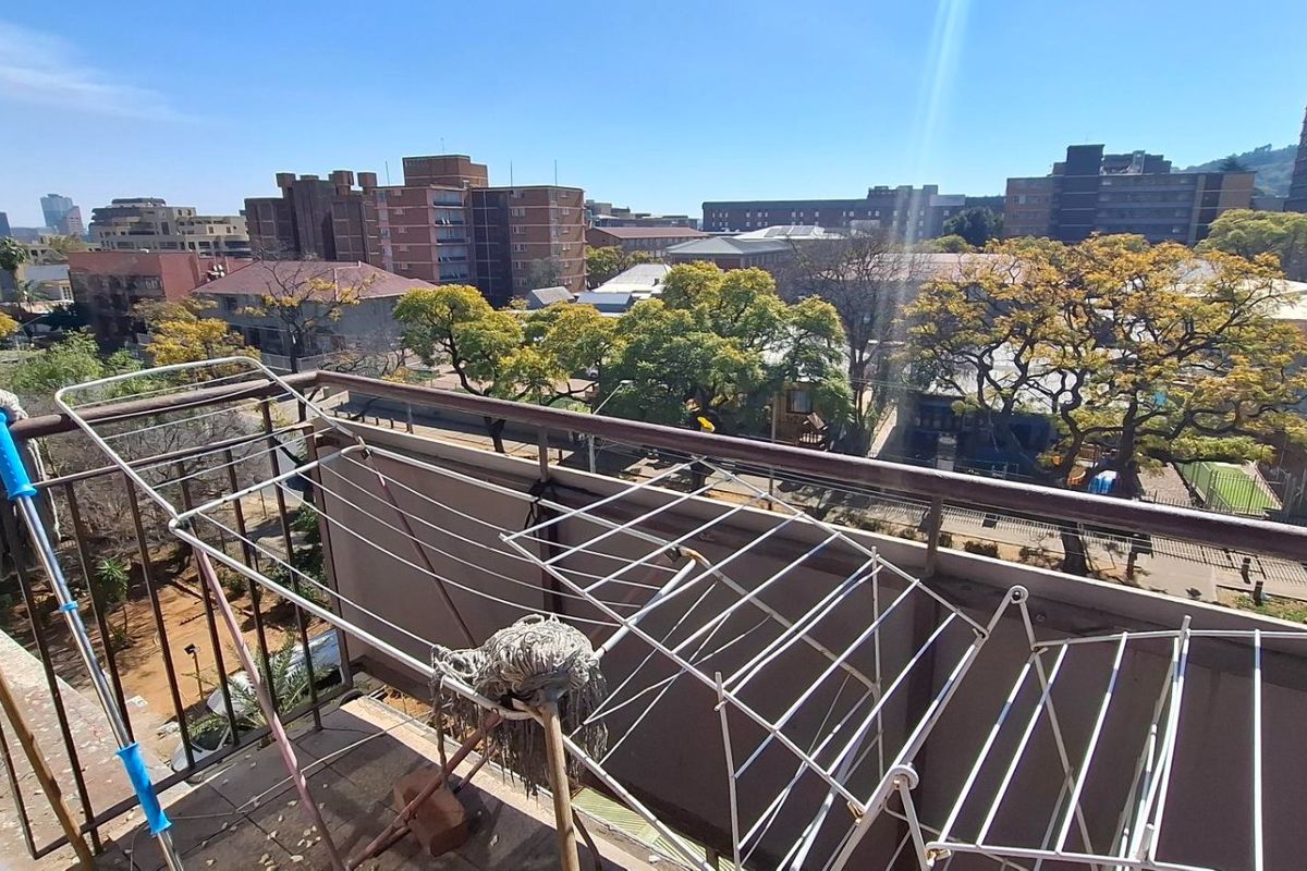 An open balcony area featuring a metal balustrade with an expansive urban view of the surrounding neighborhood and city skyline.