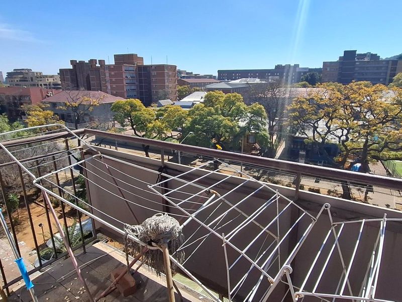 An open balcony area featuring a metal balustrade with an expansive urban view of the surrounding neighborhood and city skyline.