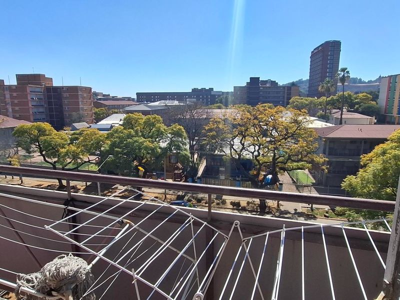 A balcony with a metal balustrade offering an elevated urban view of the surrounding neighborhood and apartment buildings.