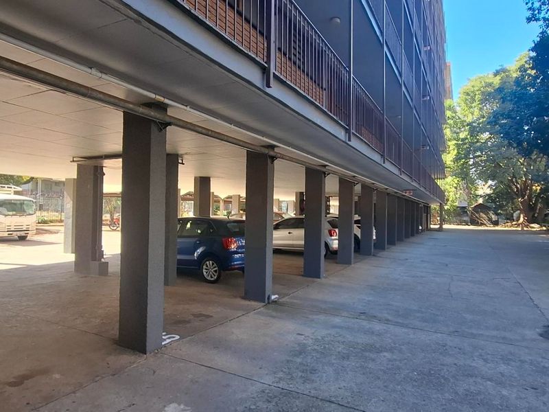 Covered ground-level parking area featuring concrete structural pillars and open access for residents.