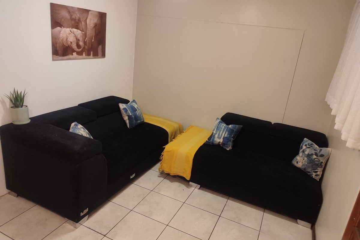 A living room area featuring neutral wall finishes and tiled flooring, providing a functional space for relaxation.