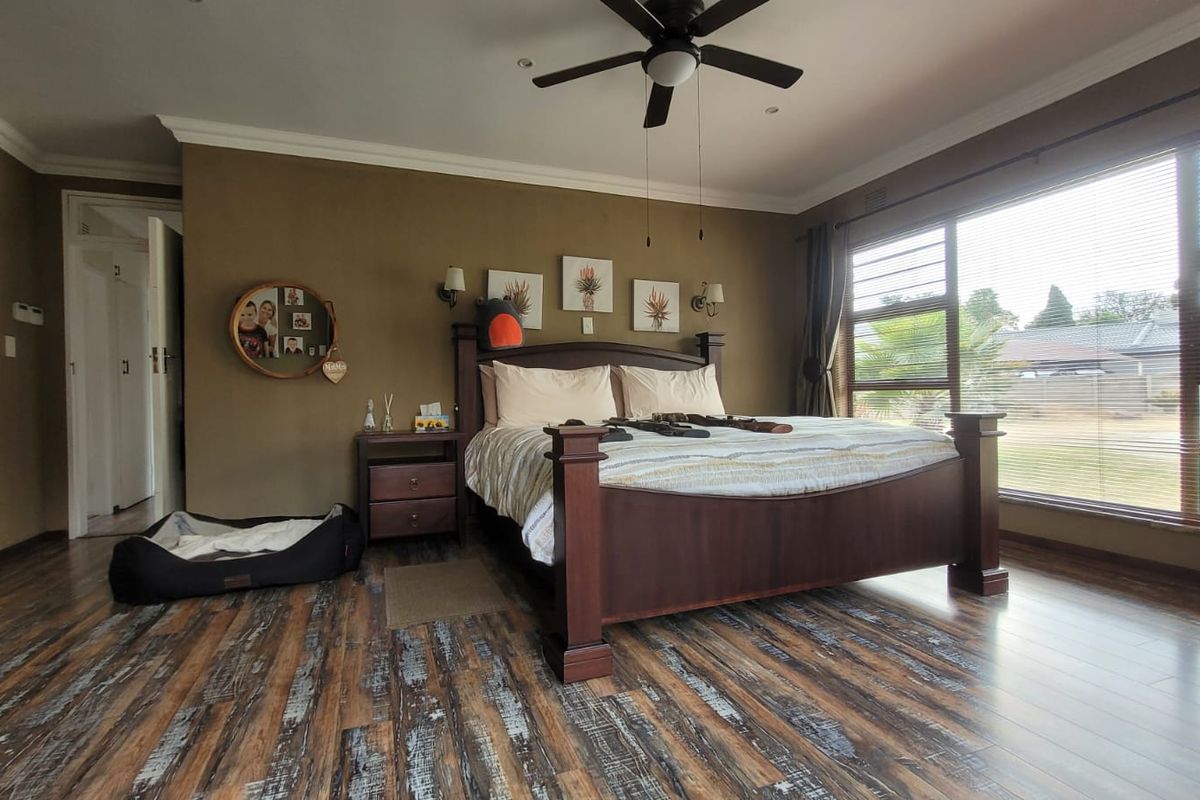 Spacious bedroom featuring durable laminate flooring, a ceiling fan, and large windows that provide ample natural light.
