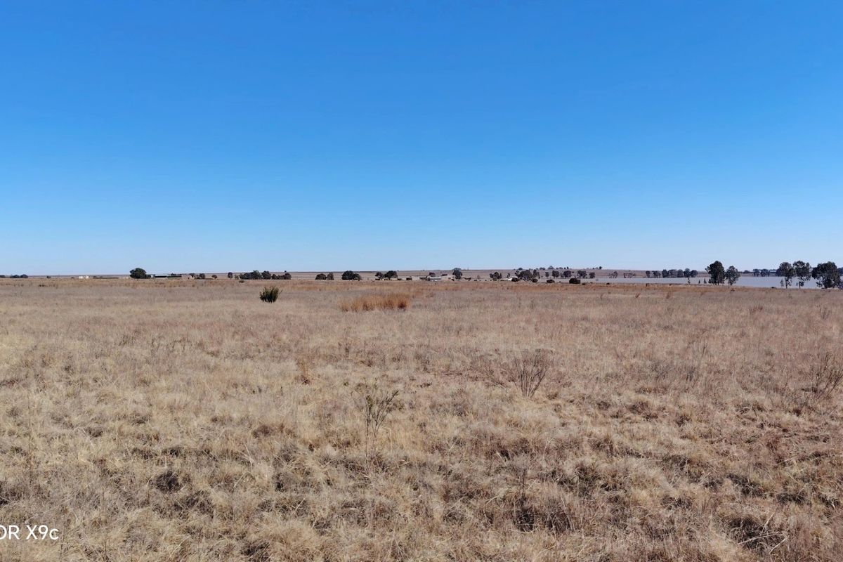 Expansive view of the open farm landscape under a clear blue sky.