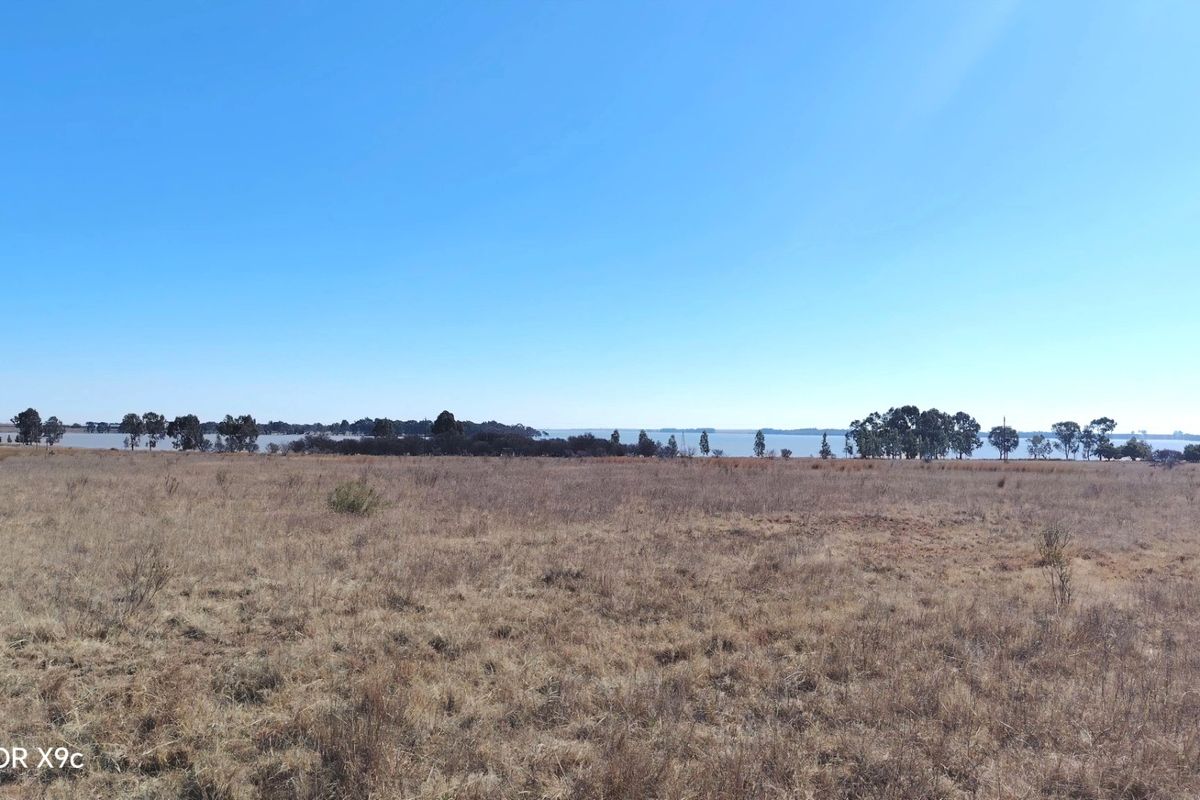 Expansive rural landscape view featuring open fields and distant water, showcasing the natural setting of the farm property.