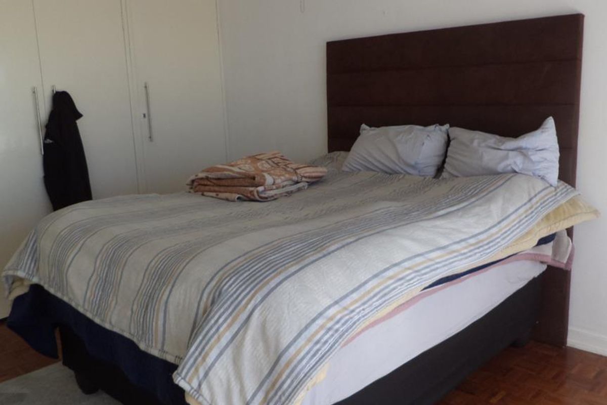 A bedroom featuring parquet flooring and built-in cupboards, providing functional storage space.