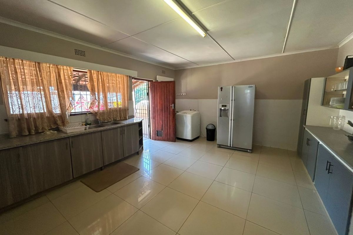 Spacious kitchen featuring tiled flooring, built-in cabinetry, and a double sink, with direct access to the exterior.